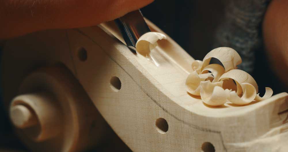 master luthier carving violin headstock